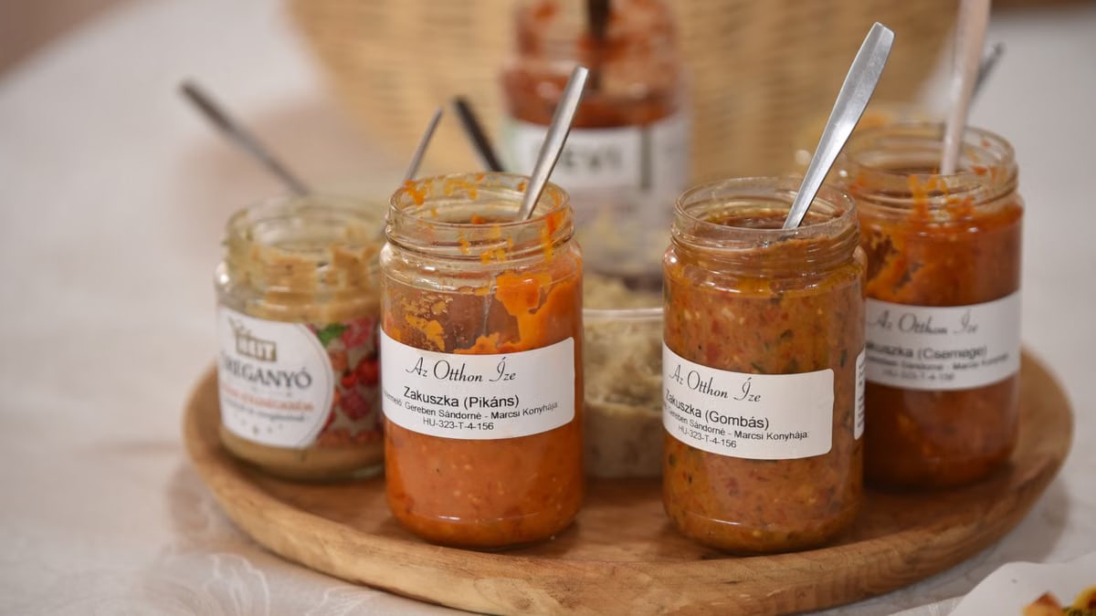 A selection of Hungarian vegetable spreads in jars on a wooden tray.